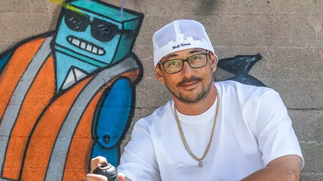 man in hat with spraypaint against mural
