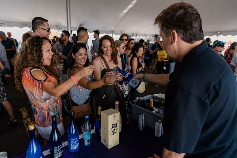 Image: people at a booth where a man is pouring wine