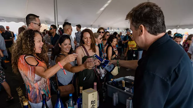 people at a booth where a man is pouring wine
