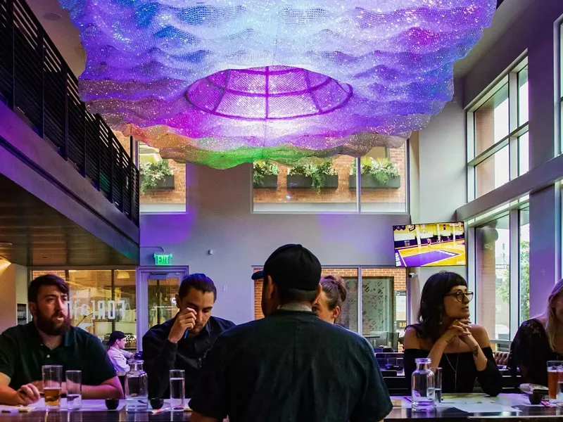 Image: people steated at a table under purple lighting