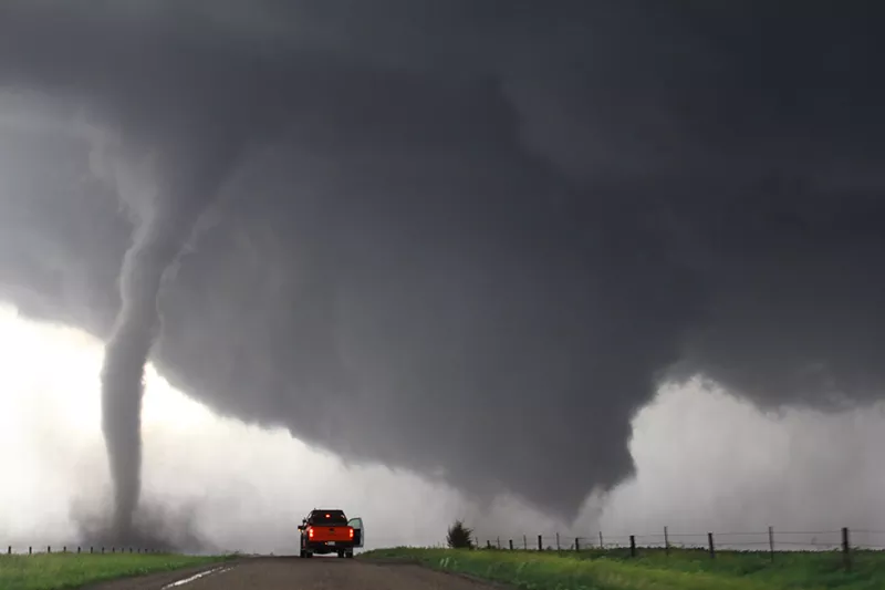 Image: Red pickup truck in front of tornado on road