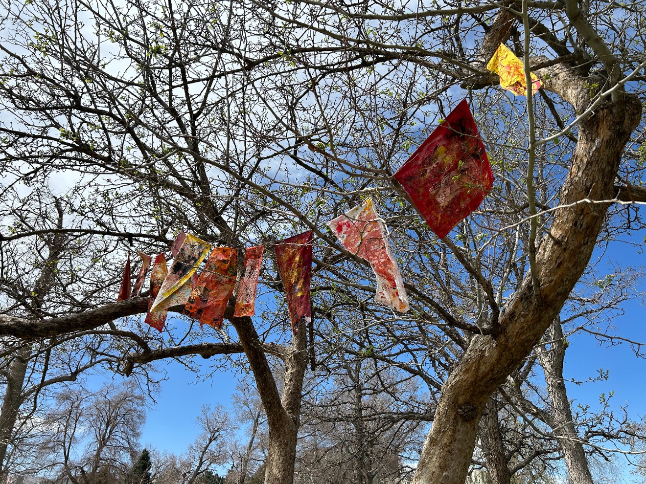 Painted flags hang from trees in La Alma Lincoln Park as part of the "Tree Tales" installation.