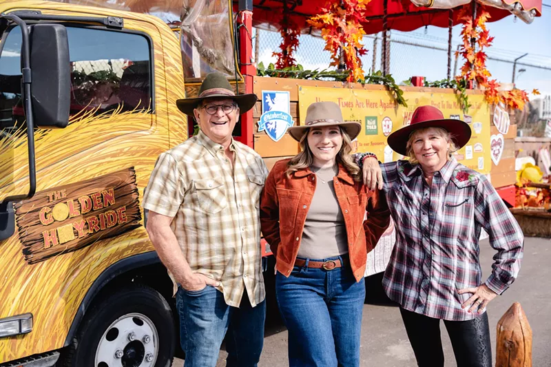 Image: three people in western-style hats posing in front of a truck