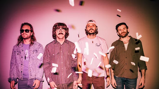 members of the jam band goose stand in pink lighting with confetti