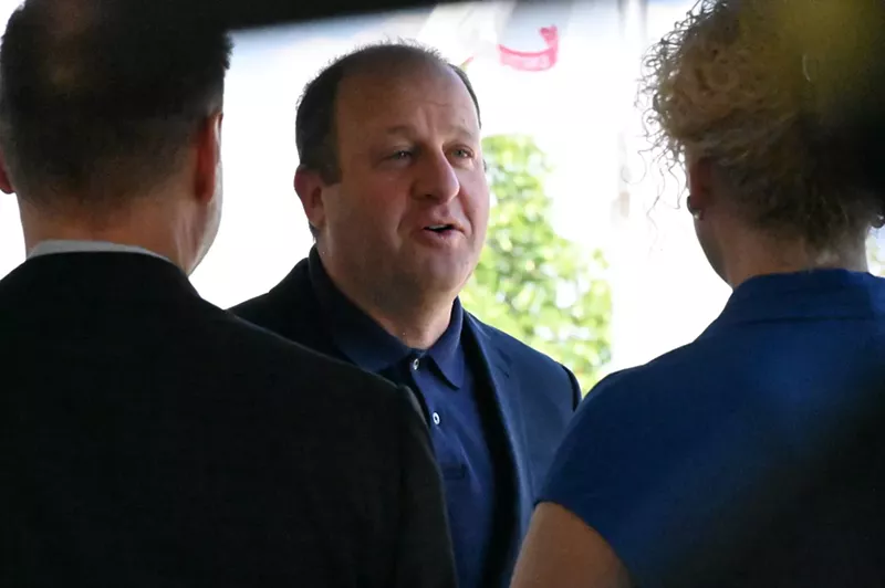 Image: A man talks to two people.