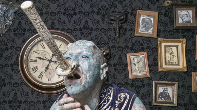 man covered in blue puzzle piece tattoos swallows a sword