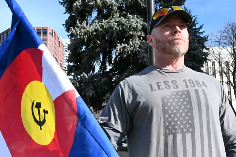 Image: A man holds up a flag.