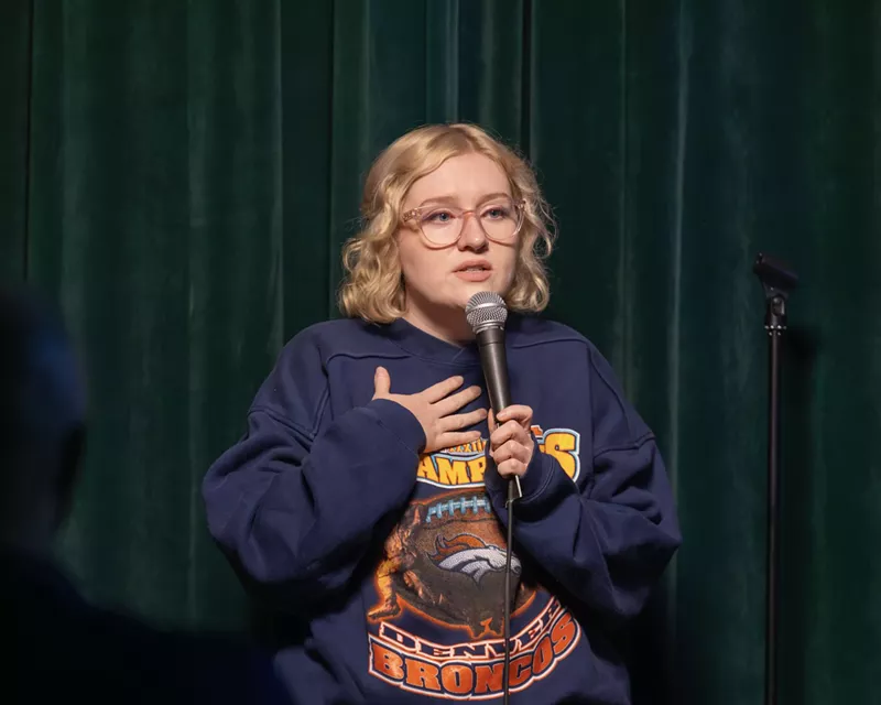 Image: blonde woman with glasses at a microphone