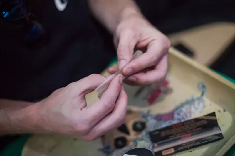 Image: Hands roll a marijuana joint over a RAW tray