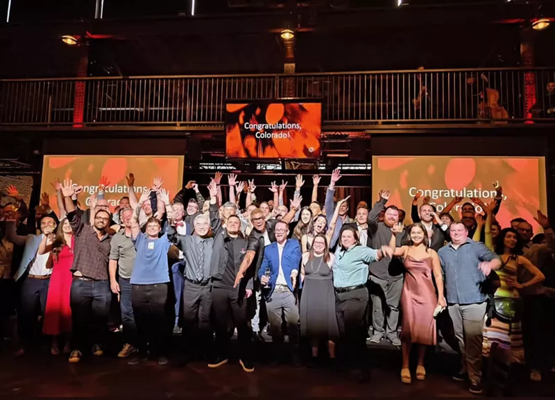 Image: large group of people posing with hands in the air
