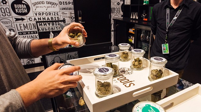 Budtender grabs jars of marijuana inside of a dispensary