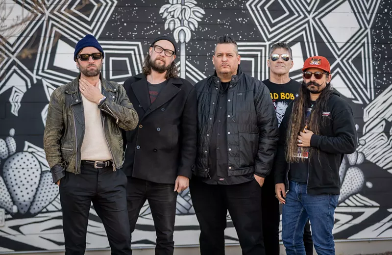Image: Five men standing against a wall.