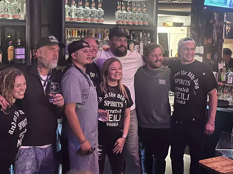 Image: a group of people posting for a photo in a bar