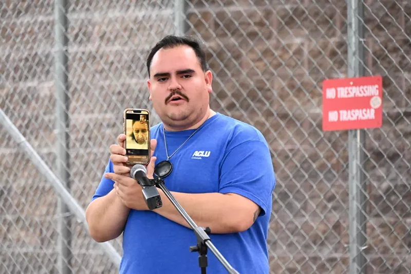 Image: A man holds up a phone.