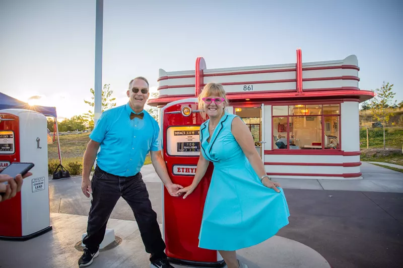 Image: couple poses in front of 1950s gas station