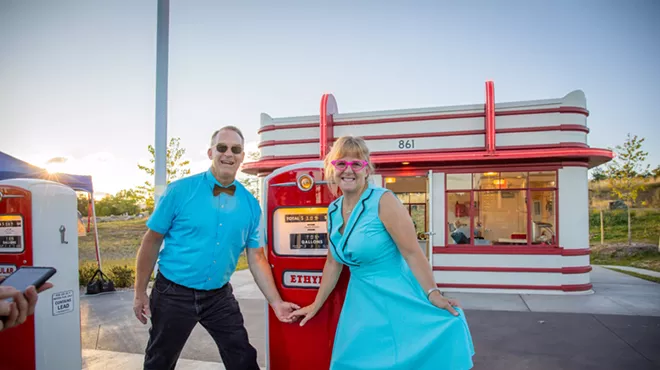 couple poses in front of 1950s gas station