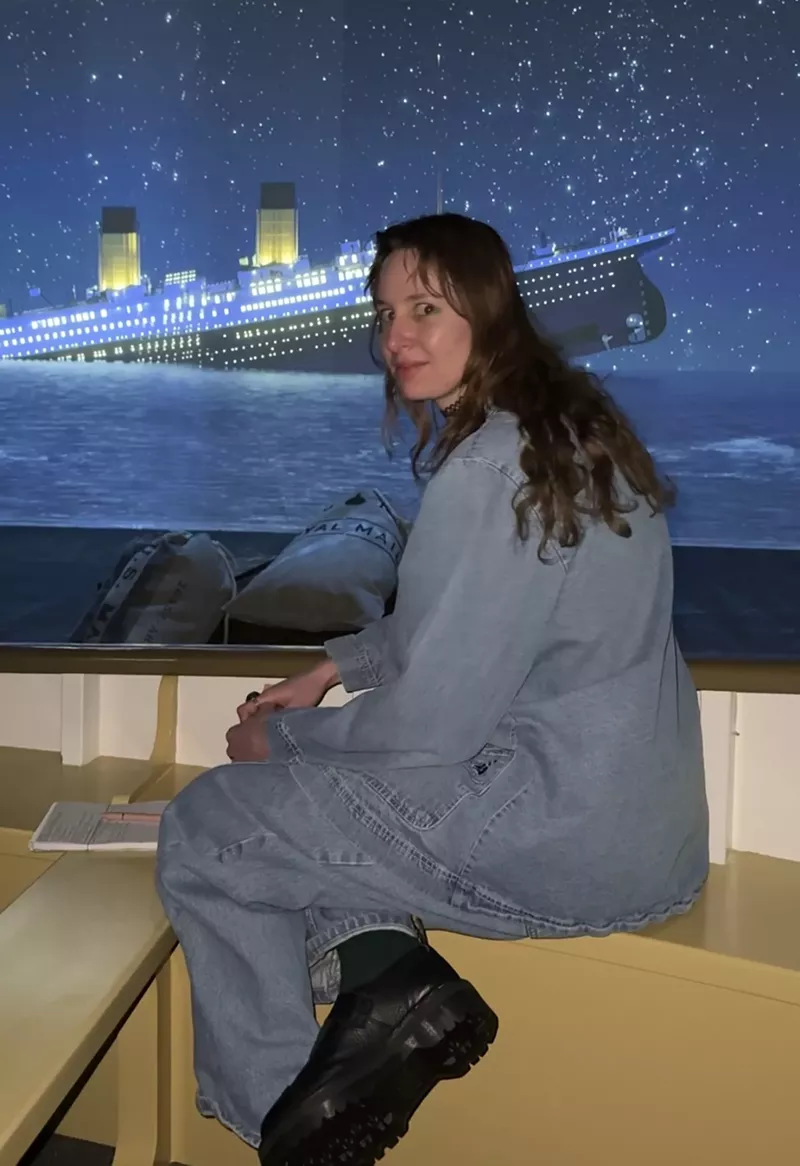 Image: A person sits in front of a screen that displays a rendering of the Titanic sinking.