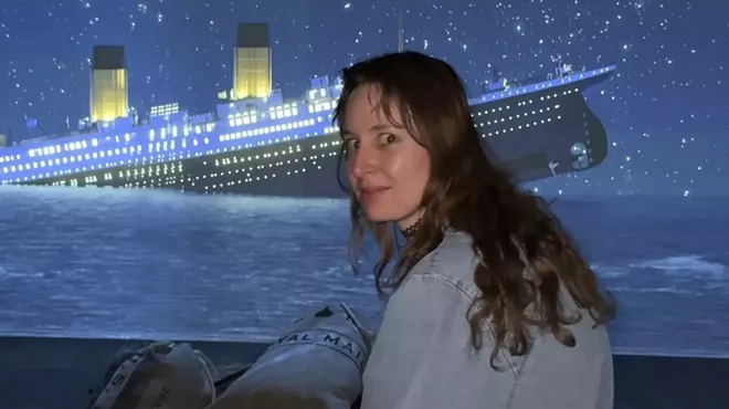 A person sits in front of a screen that displays a rendering of the Titanic sinking.