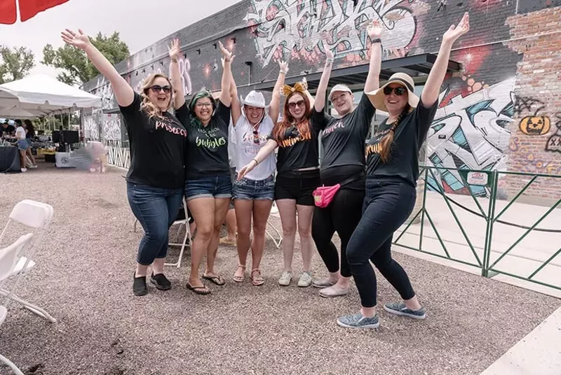 Image: a group of women posting with their arms in the air