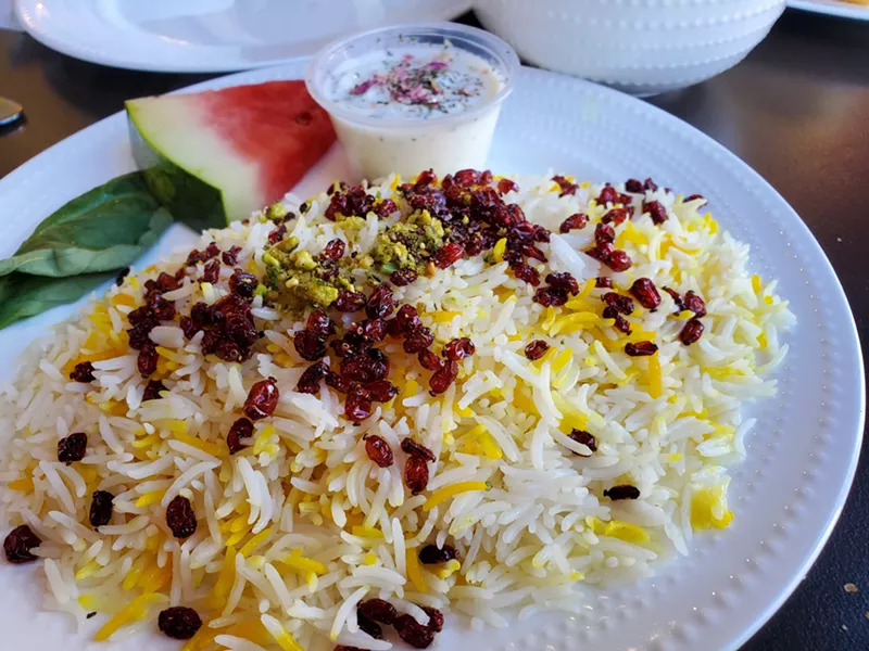Image: a plate of rice topped with barberries and pistachios.