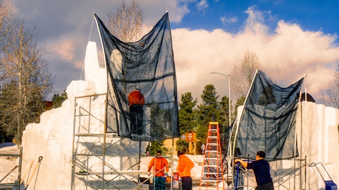 Workers build a snow sculpture with scaffolding in Breckenridge