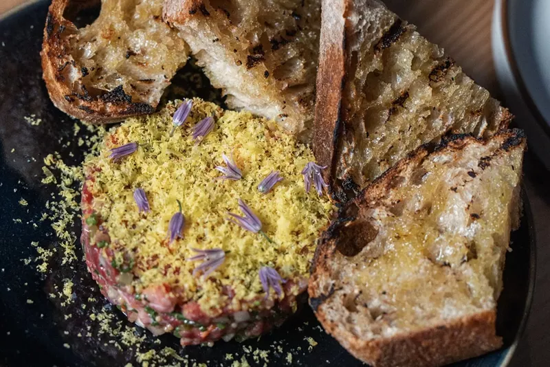 Image: Wagyu steak tartare garnished with edible flowers and served with grilled bread