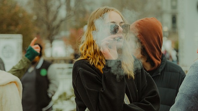 Young woman smokes joint outside