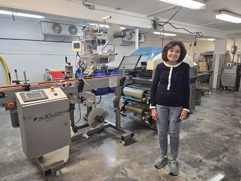 Image: a woman standing inside a sausage production facility