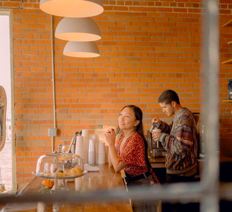 Image: two people standing behind a counter in a coffee shop