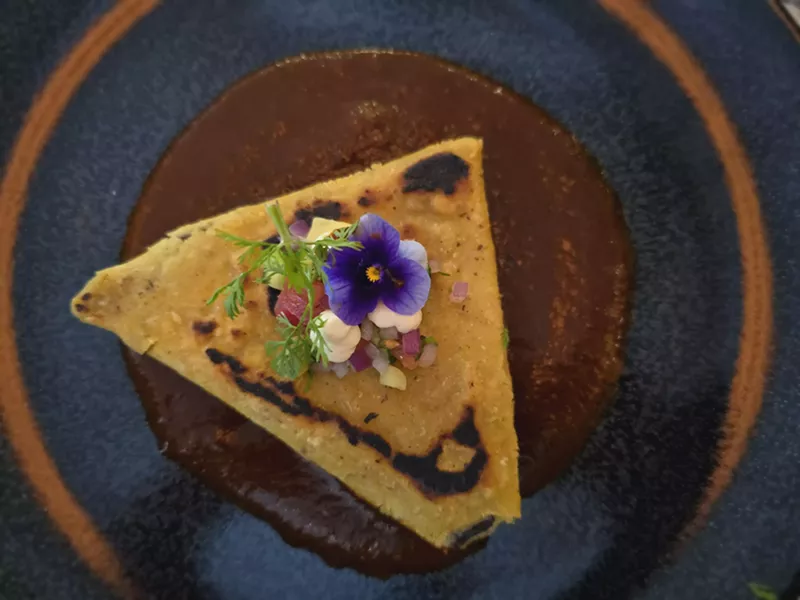 Image: a tetela on a plate over dark sauce