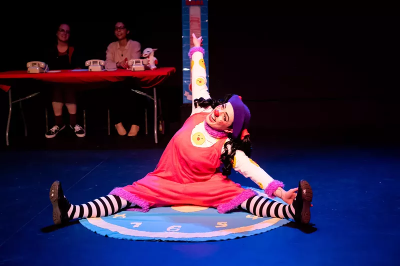 Image: woman in tights and clown nose stretching on stage