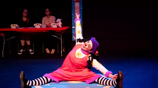 woman in tights and clown nose stretching on stage