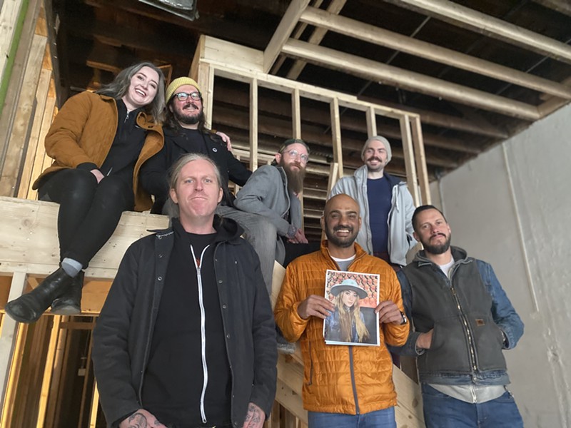 Sudhir Kudva, in orange, and his merry band of investors sit on the stairs that will soon lead to a rooftop deck at Marigold.