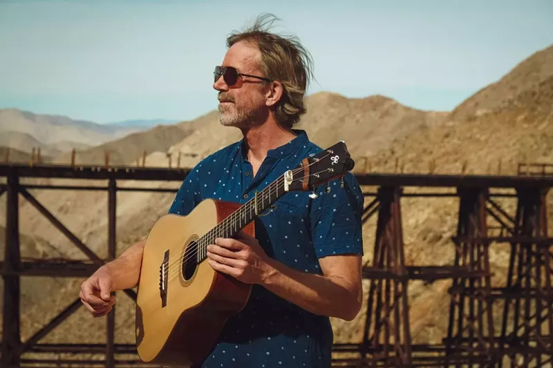 Image: man with a guitar looks at mountains