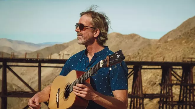 man with a guitar looks at mountains