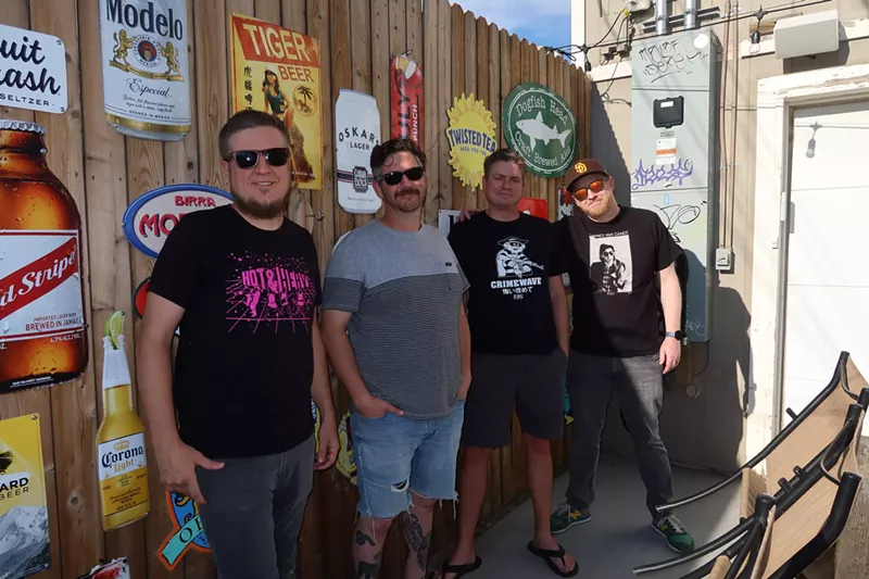 Image: four men standing in front of a bar