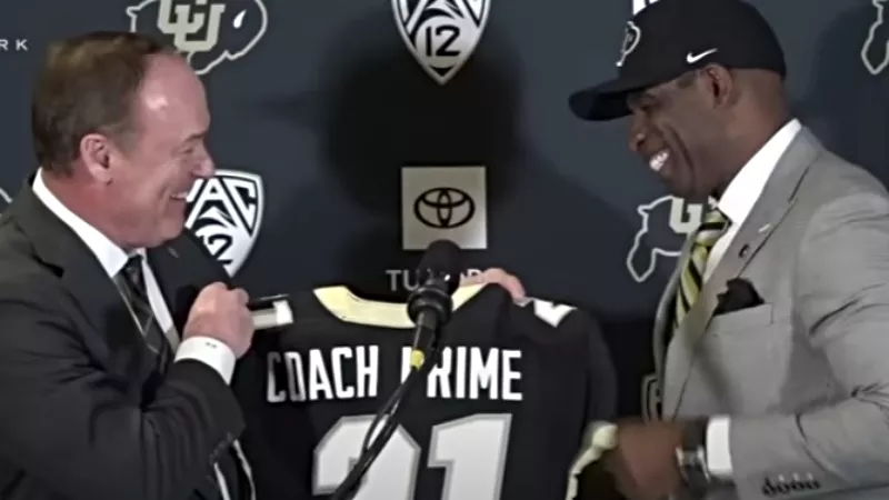 Image: CU Boulder athletic director Rick George gave new football coach Deion Sanders a "Coach Prime" jersey during a December 4 press conference.