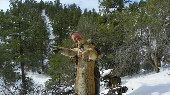 man holding dead mountain lion