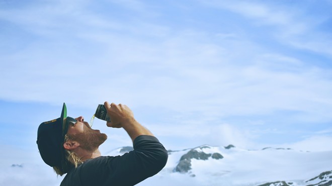 Man drinks beer on top of mountain