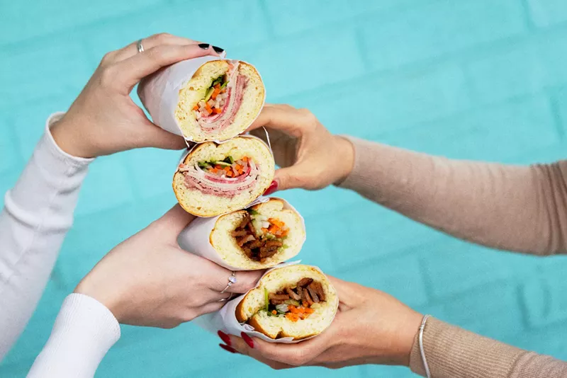 Image: hands holding four bánh mì