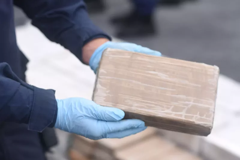 Image: Crime scene investigator holds brick of seized cocaine