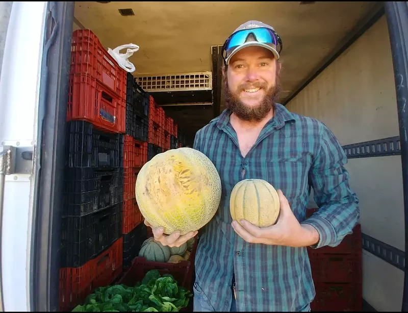 Image: a man holding two melons