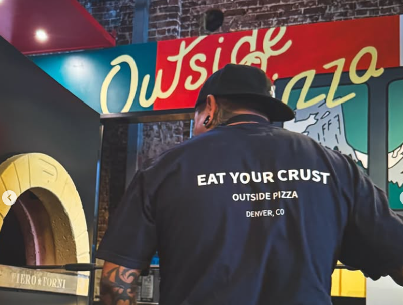 Image: person staning in front of an "outside pizza" sign
