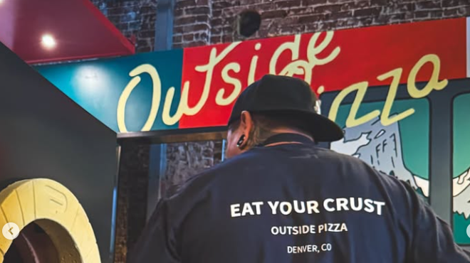 person staning in front of an "outside pizza" sign