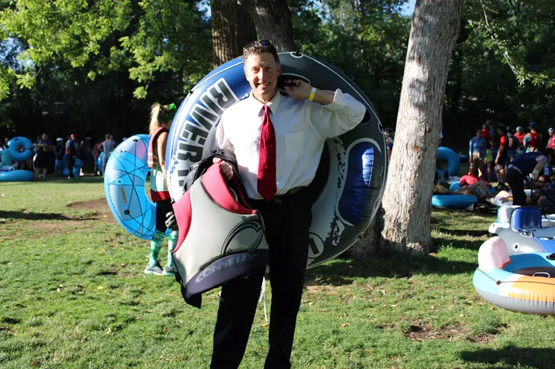 Image: A man in a suit poses with an inner tube