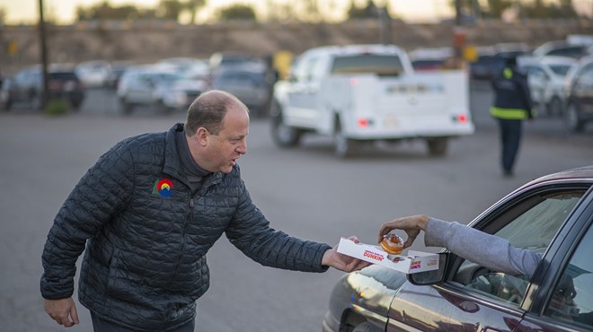 Colorado Governor Jared Polis hands out free doughnuts to a driver