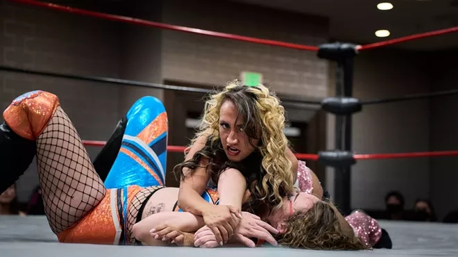 A female wrestler pins down another wrestler