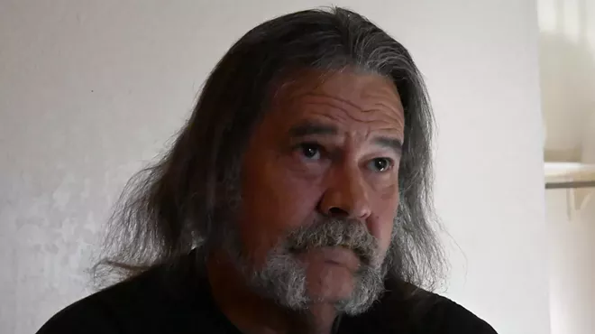 Man with long hair and beard gives interview