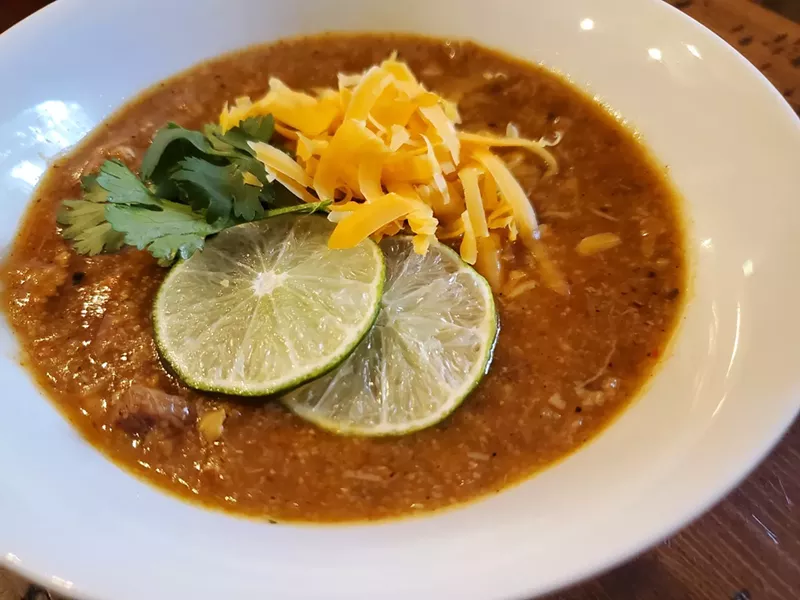 Image: bowl of green chile with lime, cheese