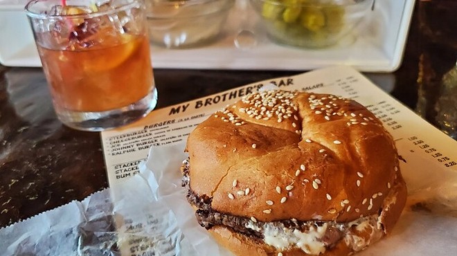 burger on wax paper with menu and drink.